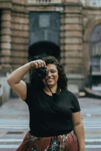 woman holding camera | therapy for women lynn, ma | women's therapist lynn, ma | women's issues therapy lynn, ma | lynn, ma | salem, MA | Winthrop, MA A happy Black woman smiling & holding a camera to her eye for focus. If you're looking for a women's therapist in Lynn, MA, we're here to support you. Our therapists can support you with parenting stress, burnout & relationships.