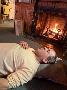 man relaxing on ground | individual psychotherapy lynn, ma | online therapy, Massachusetts | individual therapy lynn, ma | lynn, ma | swampscott, ma | saugus, ma A man with a light colored shit resting on the ground with is eyes closed near a fireplace. Representing moment of calm & emotional regulation. Learn how individual therapy in Lynn, MA can get you there!