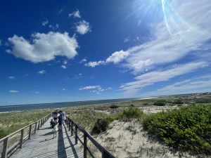A wide angle view of a wooden board walk near sand on a bright sunny day. Individual therapy in Lynn, MA is here to help you address anxiety, LGBTQIA+ identities, trauma & more. Reach out today.